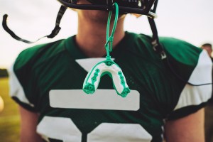 Football player with an athletic mouthguard hanging from helmet