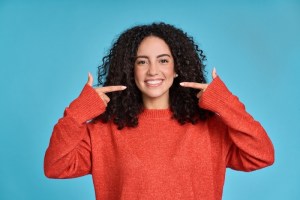 Woman smiling pointing at mouth